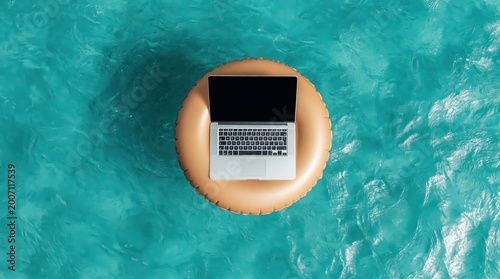 Laptop computer rests on orange inflatable ring floating in bright blue swimming pool, symbolizing remote work or vacation. High quality photo