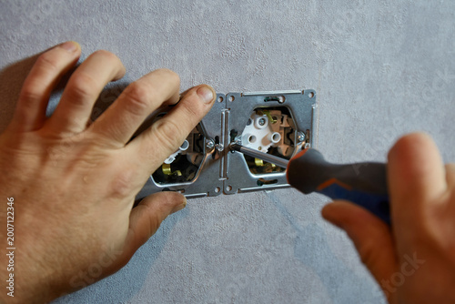 Close-up of electrician fixing wall sockets with screwdriver.
