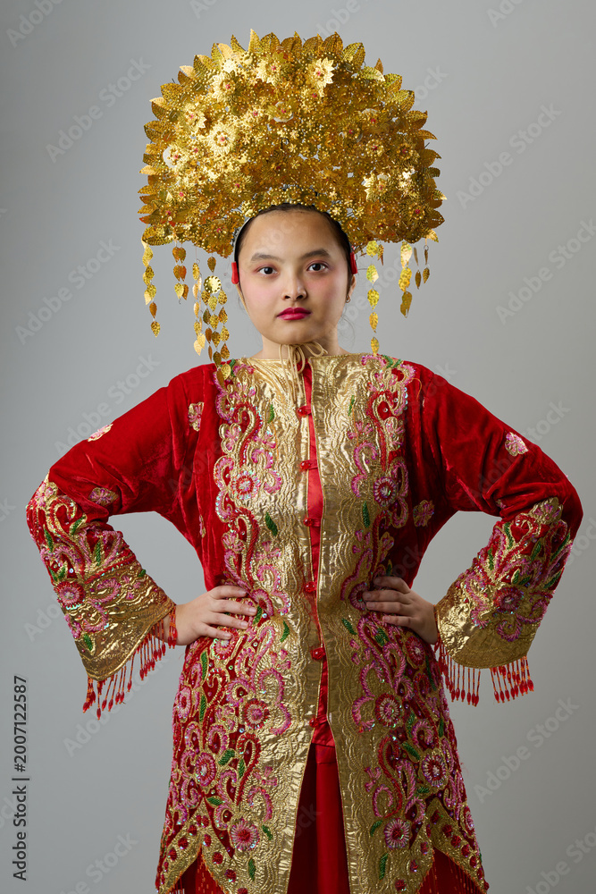 Obraz premium Young Indonesian Asian Woman in Red and Gold Traditional Ceremonial Costume With Ornate Gold Headdress