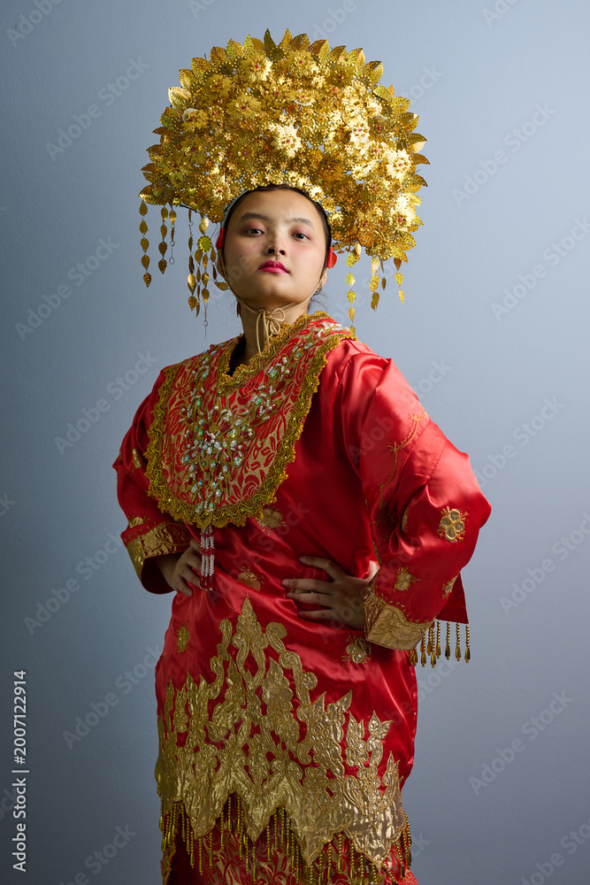 Fototapeta premium Portrait Of Indonesian Asian Woman In Red Traditional Costume With Ornate Gold Headdress And Embroidery
