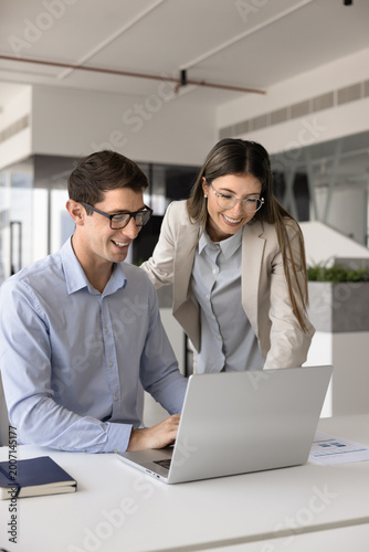 Obraz na płótnie Male female workmates looking at laptop screen with joyful expression, watching