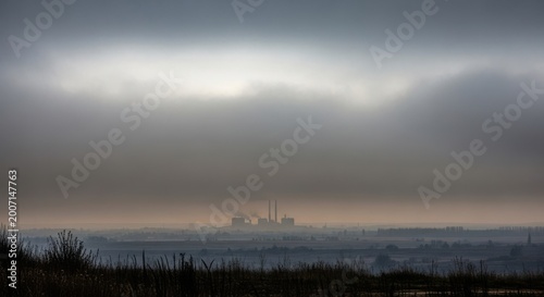 Industrial Factory Silhouetted Against Overcast Sky and Foggy Horizon