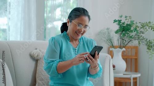 Elderly asian woman interacting with smartphone, expressing surprise and curiosity while browsing or receiving information.
