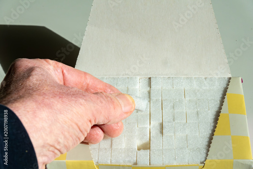 Photography Stockholm, Sweden A hand reaches in a box of sugar cubes
