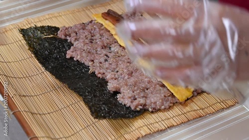 Hands rolling traditional Korean kimbap with multi-grain rice and various ingredients