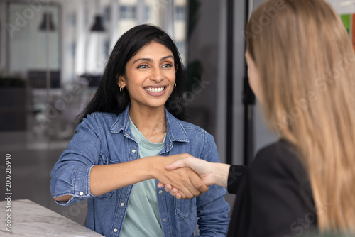 Foto Happy Indian woman shaking hands with female HR manager, start or finalize job interview in company office, smiling, feeling satisfied with recruitment outcome, got job of dream