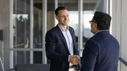 фотографія Two businessmen greeting each other with handshake standing in office hallway
