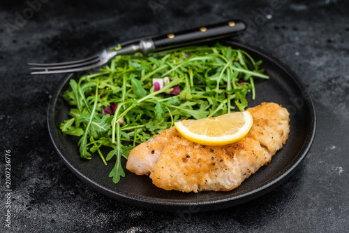 Healthy seafood meal with fried snapper fillet and green salad. Balanced dinner plate.