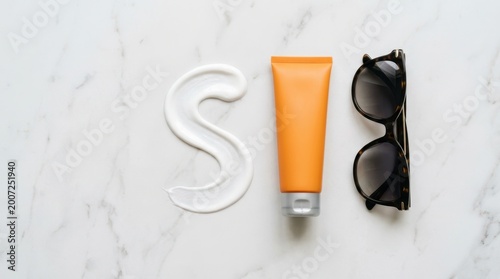 Sunscreen and sunglasses arranged on a marble surface for summer protection