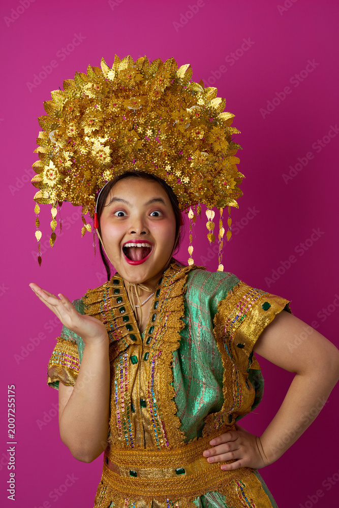 Fototapeta premium Joyful Indonesian Asian Woman Wearing Elaborate Gold Headdress and Traditional Costume Celebrating Cultural Festival