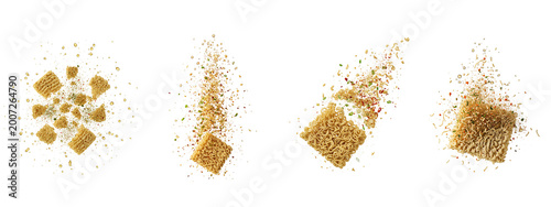 Four floating instant noodle blocks with scattered dry seasoning on black