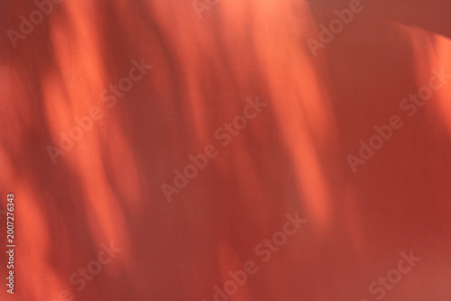 Sunlight casting abstract shadows on red wall