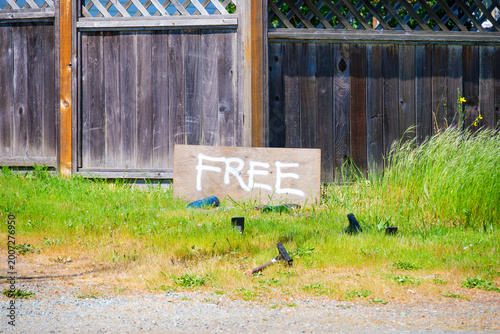 Photos Wooden 'FREE' sign rests on a grassy patch near a wooden fence