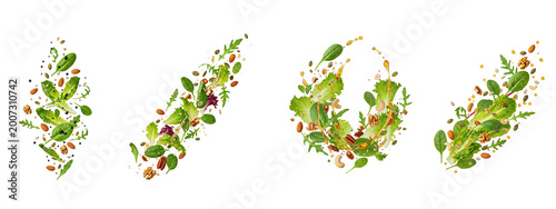Fresh salad leaves with nuts and dressing flying on black background