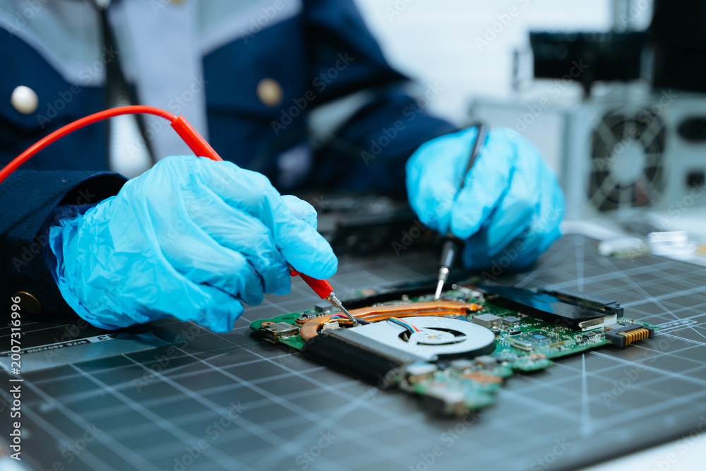 Naklejka premium Technical hardware repair. Hands in blue gloves using multimeter probes to test a computer circuit board, emphasizing precision engineering