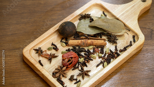 Aromatic Indian Spices Including Star Anise Cinnamon and Cardamom Dropping on Wood Surface