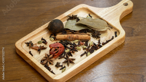 Aromatic Indian Spices Including Star Anise Cinnamon and Cardamom Dropping on Wood Surface
