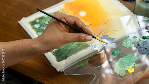 Close Up of Woman Hand Holding Transparent Palette Blending Green and White Watercolor