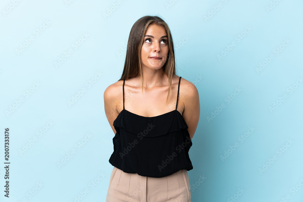 Obraz premium Young Uruguayan woman isolated on blue background and looking up