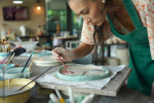 A young woman makes a ceramic plate in a workshop