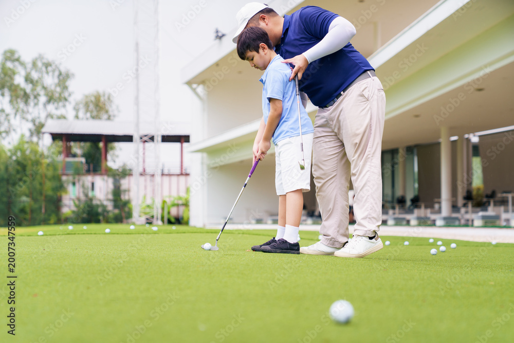 Fototapeta premium Golf instructor teaching young student to putt at practice green