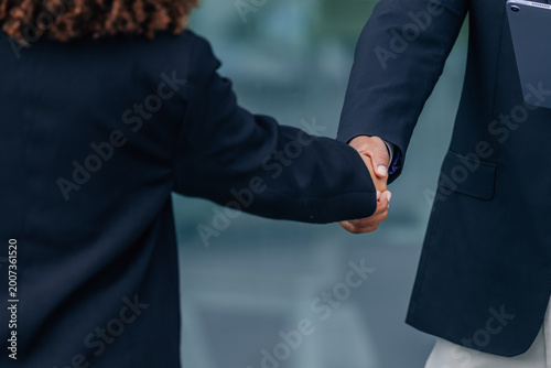 Bild auf Leinwand Two business professionals shaking hands outdoors, symbolizing agreement, partne