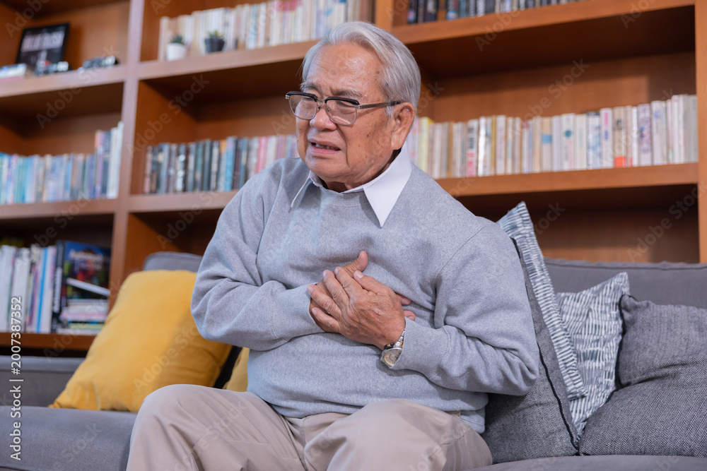 Fototapeta premium Elderly man grab his chest with hand suffer from chest pain in a living room