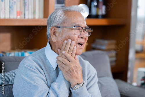 Elderly man grab his cheek suffer from toothache at home