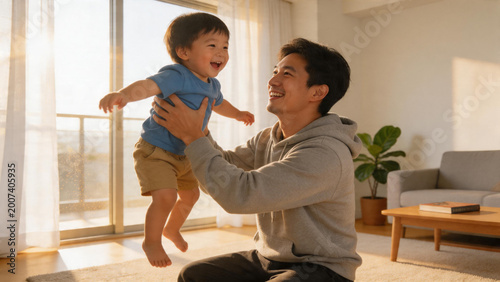 Pleased oriental dad hoisting his giggling young child inside a brightly-lit stylish flat. Authentic instance of paternal connection, adoration, and merry recreation in a homey space.