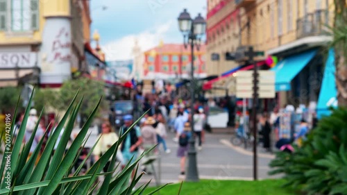 Blurred outdoor scenery featuring crowd walking on street in Nice city during sunny summer afternoon.