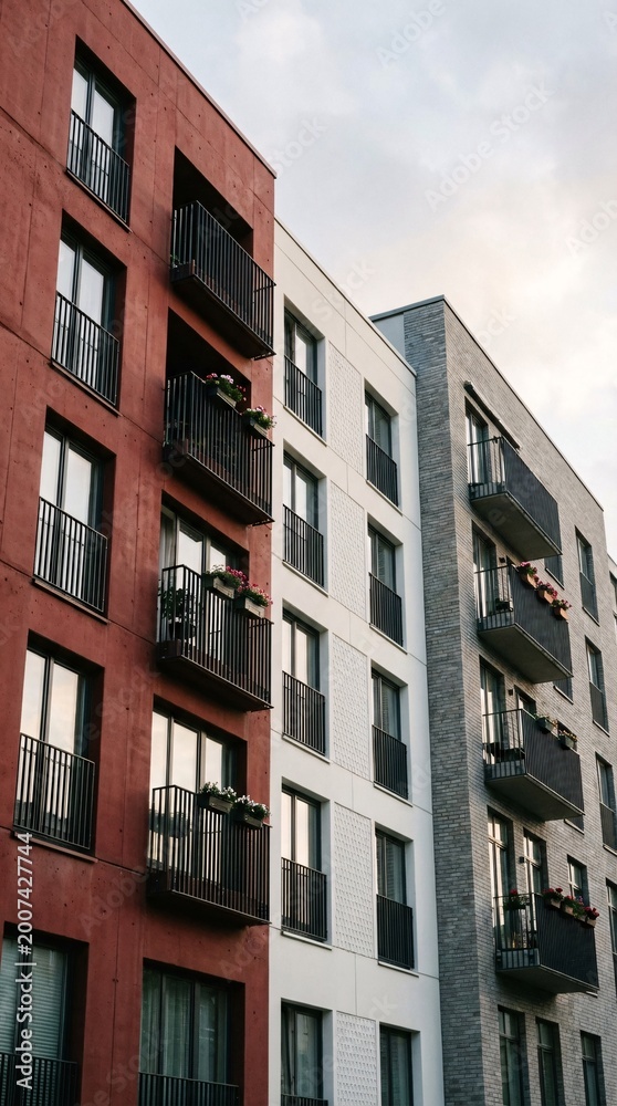 Fototapeta premium Modern Apartment Buildings with Balconies and Windows Against a Cloudy Sky.
