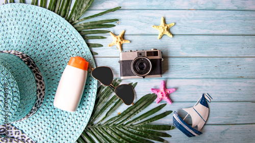 Summer Fashion woman big hat and sunblock with accessories item, vintage camera go to travel in the beach. Tourism travel on holiday happy leisure and destination trip.  wood blue background. Summer