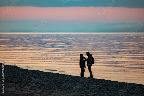 Canvastavla Silhouettes of a couple in love on a sandy beach by the sea at sunset