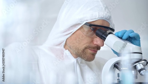 Photos Scientist in ppe analyzing samples with microscope