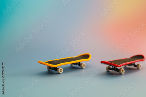 Foto Two small toy skateboards in yellow and red stand on a smooth surface against a soft gradient background