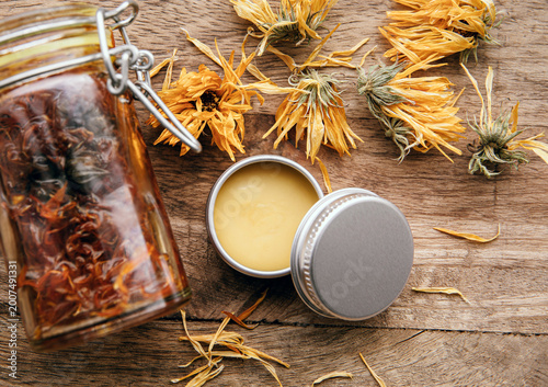 Tableau sur toile Making homemade Calendula officinalis common marigold cold infusion oil in glass jar and handmade medicinal salve in metal jar