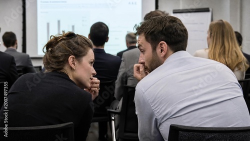 Business Colleagues Whispering and Discussing Privately During Professional Presentation