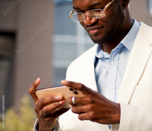 African American man checks his phone in front of a modern building