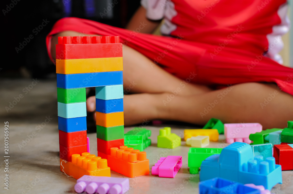 Naklejka premium Close-up of a child’s hands playing with colorful building blocks (LEGO-style toys). The image highlights creativity, learning through play, and fine motor skill development in early childhood. Bright