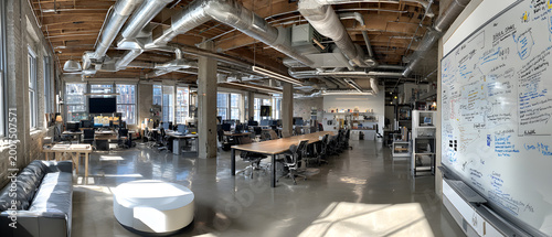 Open plan loft office with long communal table and whiteboard in bright industrial workspace