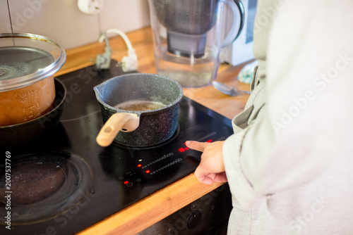 Person Adjusting Temperature on Modern Induction Electric Cooktop in Home Kitchen