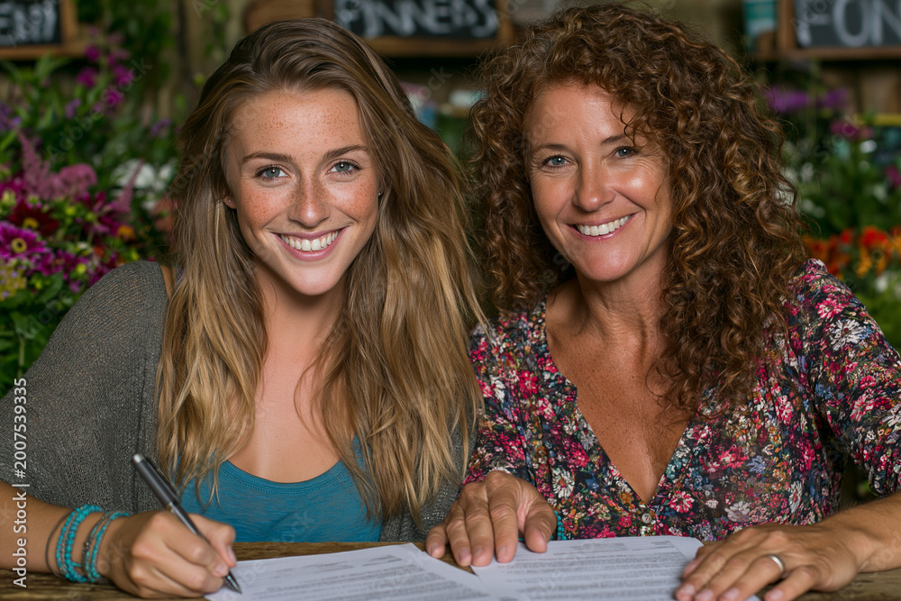 Fototapeta premium Mother and daughter signing documents together at table