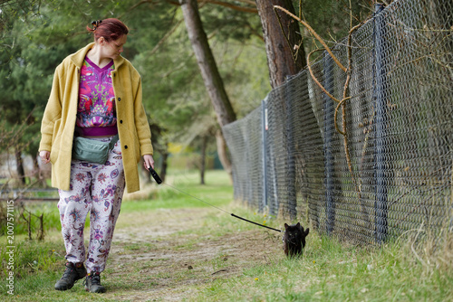 Woman walking a cat on a leash.
