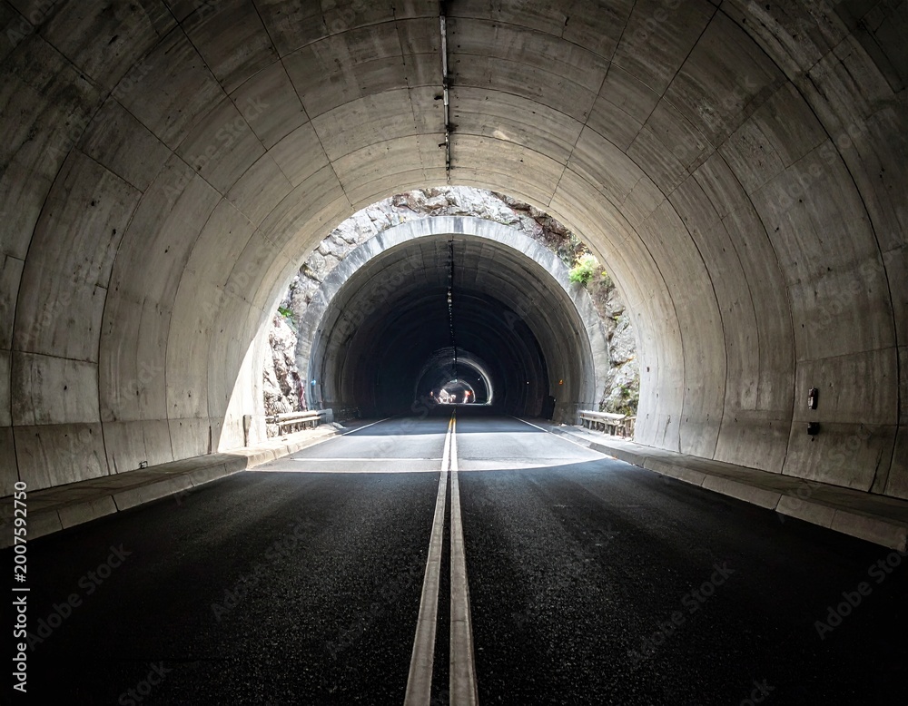 Obraz premium Perspective shot of road leading through a tunnel with light at end