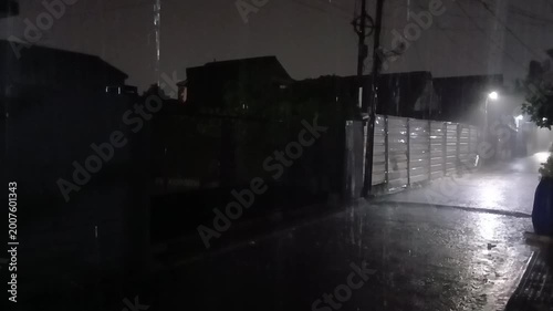 Nighttime street scene during rainfall with low visibility and street lighting, capturing a quiet and atmospheric rainy environment