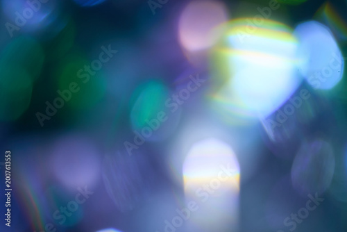 Abstract blur iridescent lens flare and purple bokeh background. Shimmering blue light leaks with rainbow prism effects create a magical, futuristic atmosphere for creative graphic design projects.