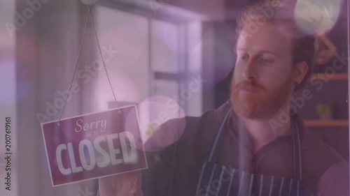 Shop worker opening shop, flipping CLOSED sign to OPEN, glass reflections layering bokeh