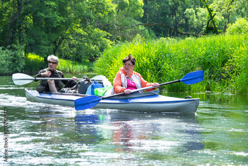 Elderly pair kayaking on a peaceful river in a Vuoksa kayak, healthy active lifestyle, mature age travel and wellness.