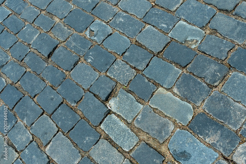 Cobblestone pavement texture top view. Ancient stone blocks of a city street road surface. Grey granite sett stones pattern for architectural background