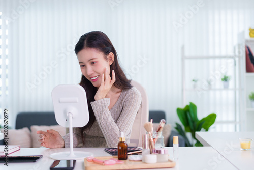Obraz na plátně Asian women applying skincare serum checking mirror face reflection enjoying bea